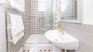 Une salle de bain moderne avec une douche à parois de verre, un lavabo blanc et un porte-serviettes.