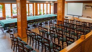 A conference room with wooden chairs and tables, a projector screen, and large windows.