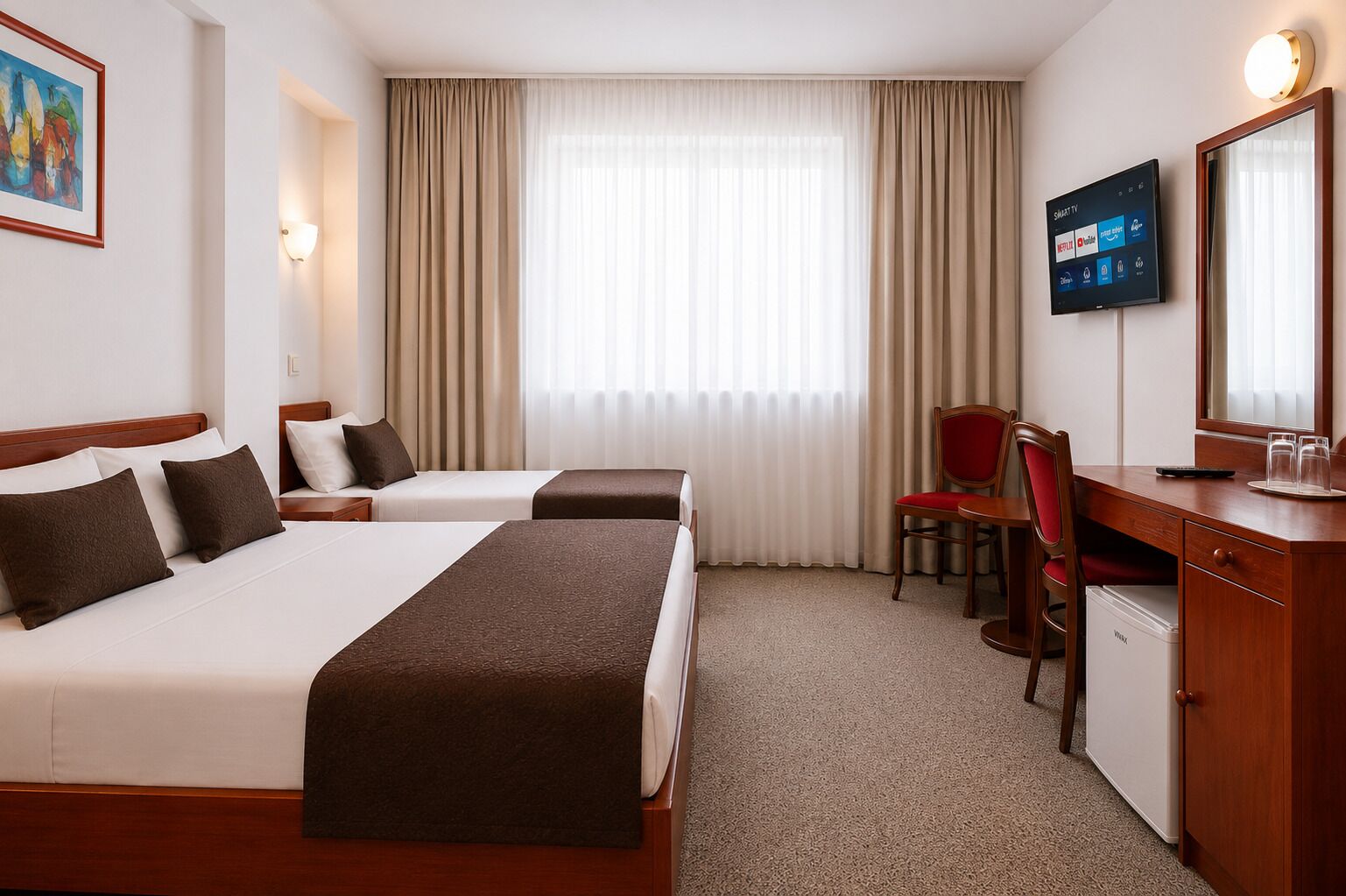 Habitación de hotel con dos camas, un escritorio con una silla, un televisor y un refrigerador.