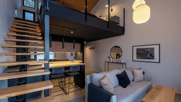 A modern interior with a staircase, kitchen, dining area, and a sofa.