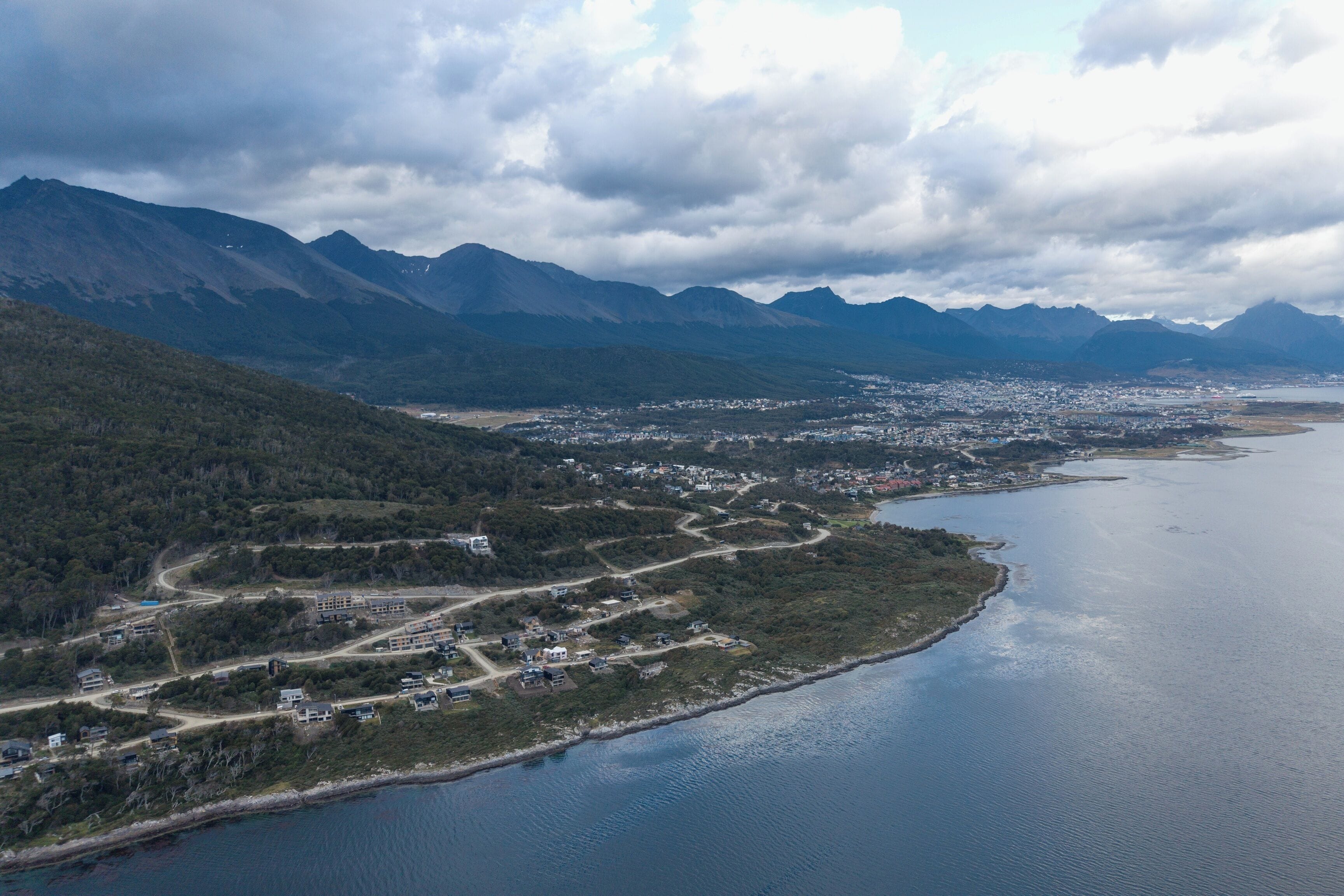 A coastal town with a river, mountains, and a dense cluster of buildings.