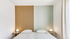 Une chambre moderne avec un lit, deux tables de chevet et un mur recouvert de panneaux en bois.