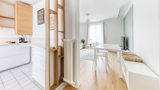 Une cuisine moderne avec des meubles blancs, une porte en bois et un radiateur.