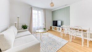 Un salon moderne comprenant un canapé, une table basse ronde, un téléviseur et un coin repas avec des chaises.