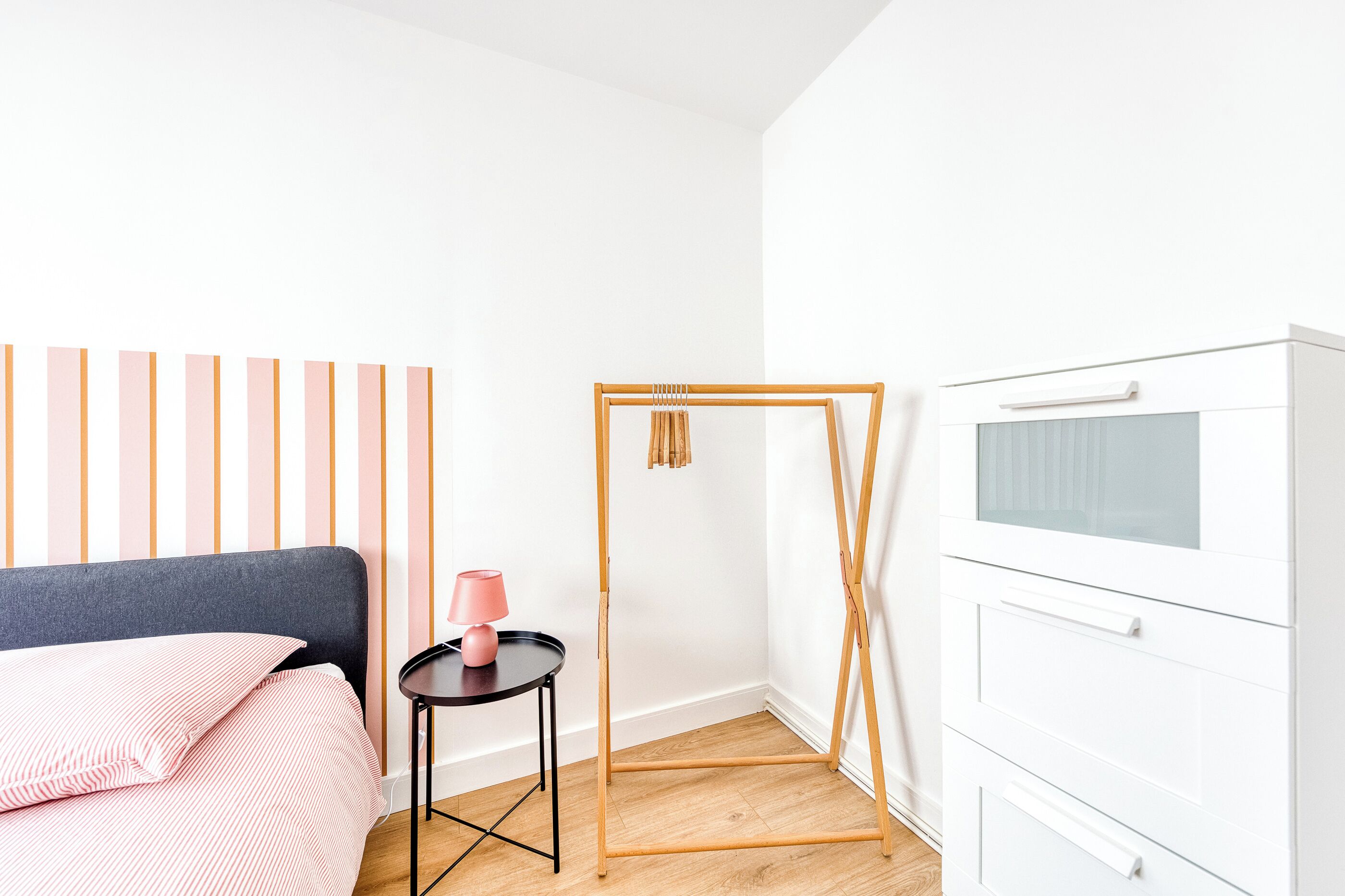 Un dormitorio con una cama, una mesita de noche, un armario y un tocador de madera con un espejo.