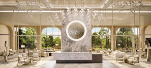 A spacious lobby with a marble reception desk, modern furniture, and large windows offering views of the outdoors.