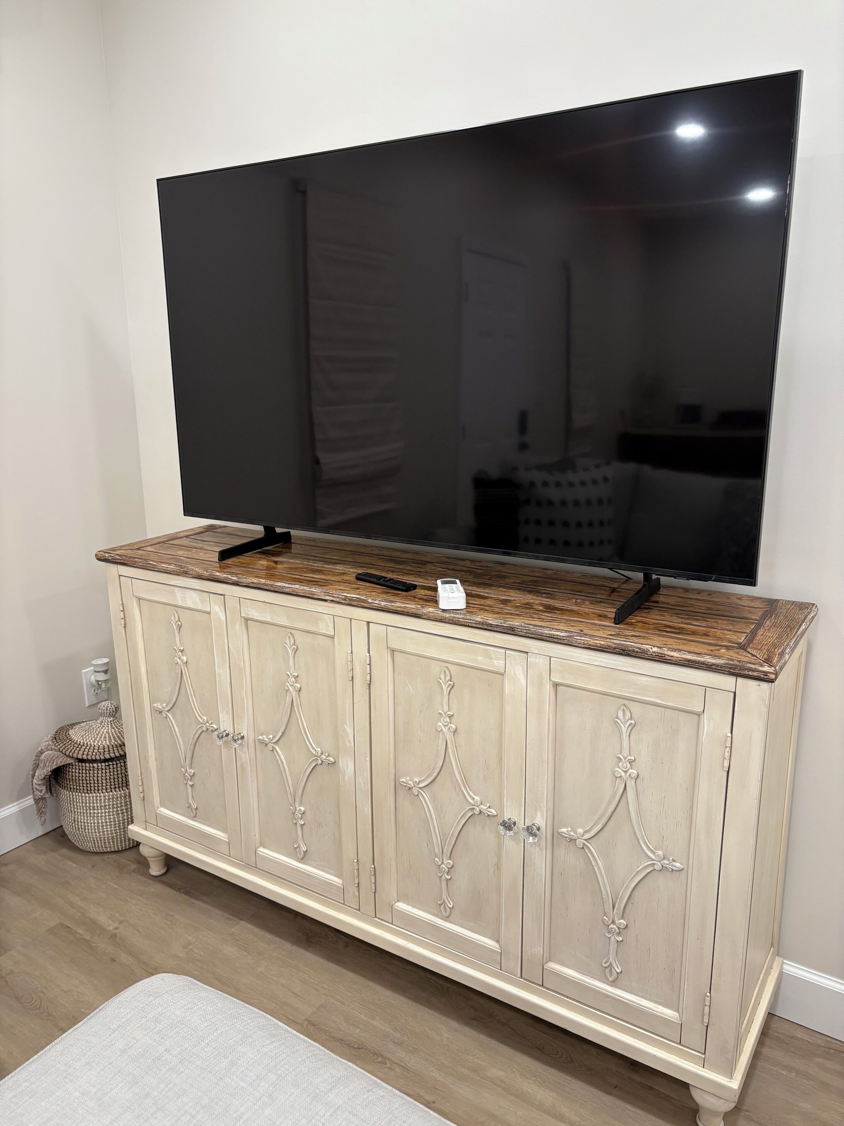 A TV on a cabinet with ornate handles and a wooden top.
