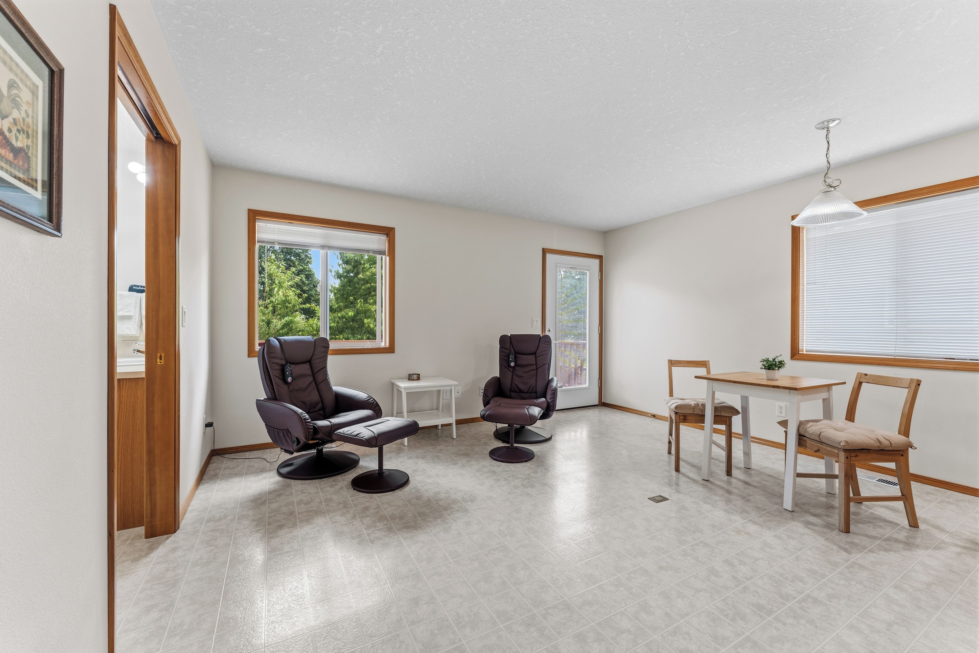 A room with two massage chairs, a small table, and a window with blinds.