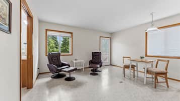 A room with two massage chairs, a small table, and a window with blinds.