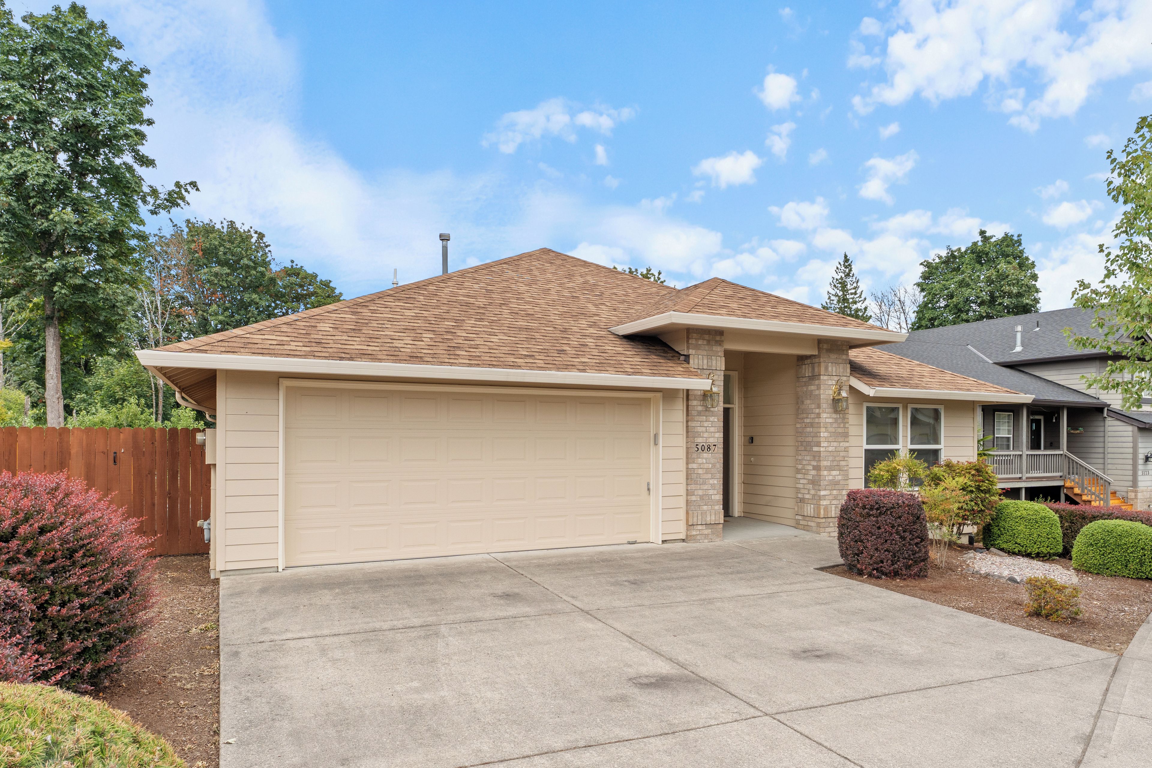 A two-story house with a garage, a brick exterior, and a well-maintained front yard.
