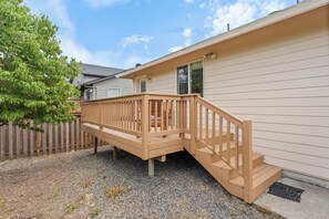 A wooden deck with a staircase leading to a house with beige siding. - 3 Bedroom House in Suburban Retreat (Gresham)