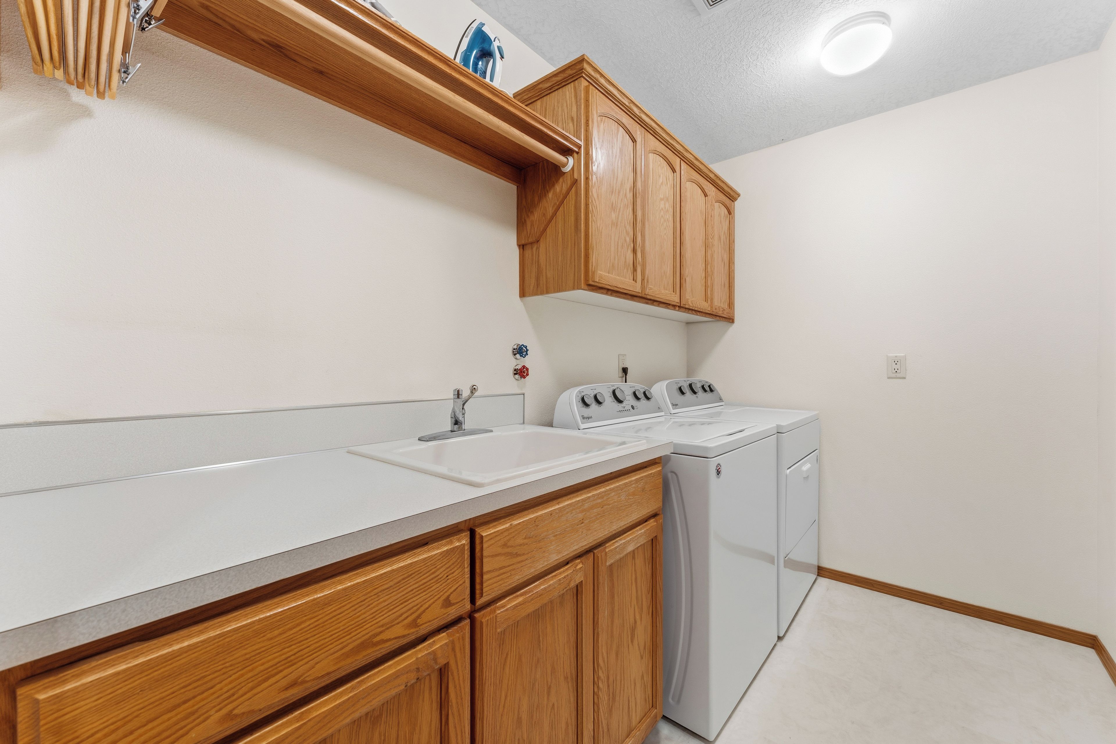 A kitchen with wooden cabinets, a white countertop, a sink, a stove, and a washing machine.