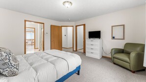 Une chambre à coucher avec un lit, une commode, une télévision et une chaise.