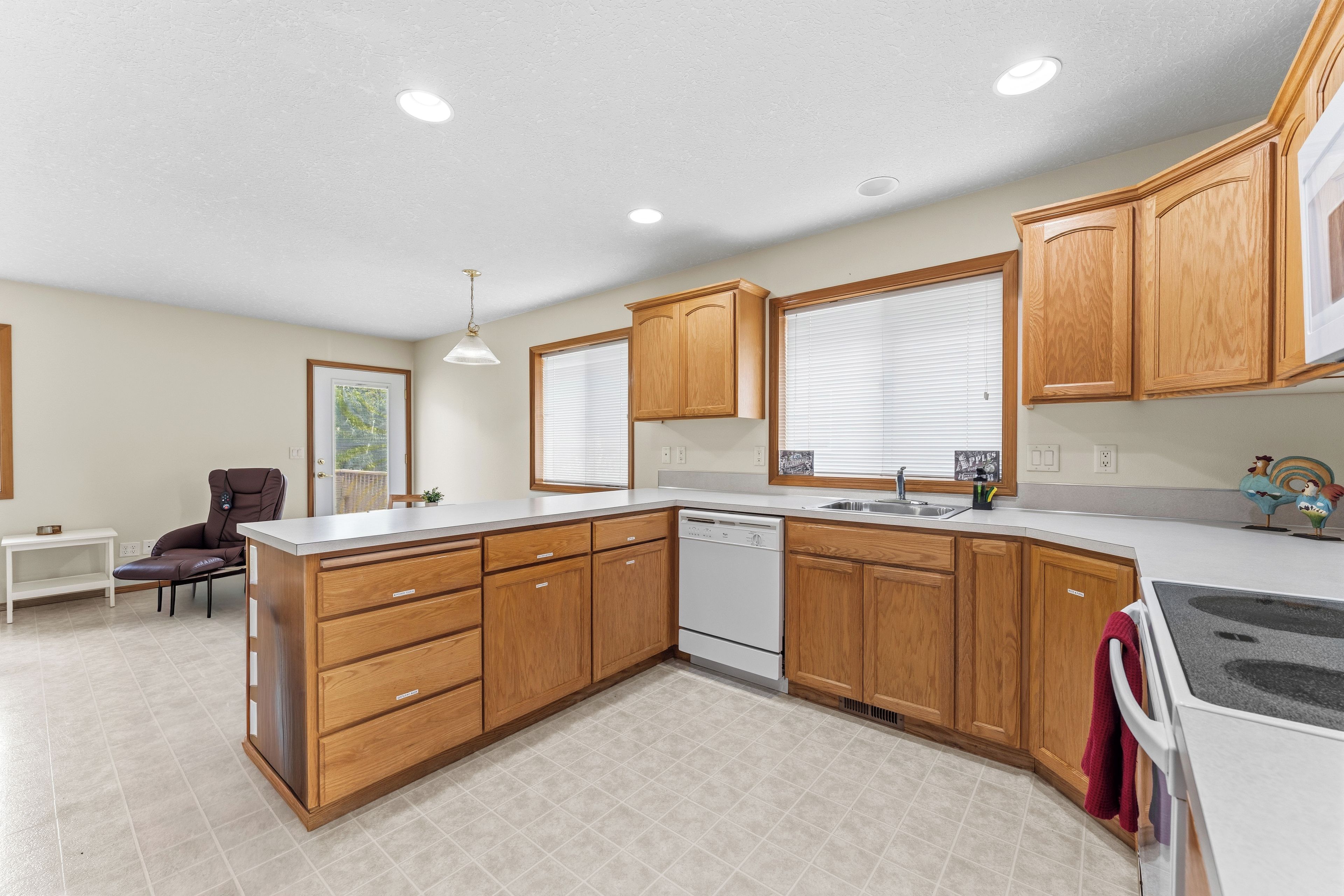 A modern kitchen with wooden cabinets, a built-in dishwasher, and a large island with drawers.