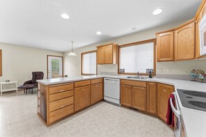 A modern kitchen with wooden cabinets, a built-in dishwasher, and a large island with drawers. - 3 Bedroom House in Suburban Retreat (Gresham)