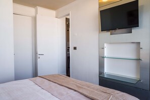 A bedroom with a bed, a television mounted on the wall, and a shelving unit. - Bright 1BR Las Condes  Apartment in Prime location (Las Condes)