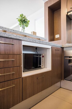 A kitchen with wooden cabinets, a built-in microwave, and a stainless steel oven. - Chic 2 Bedroom Apartment for 3 with Pool And Gym (Las Condes)