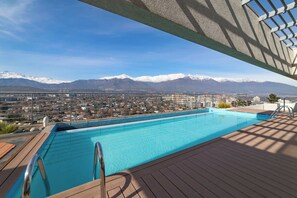 A swimming pool with a view of a city and snow-capped mountains in the background. - Bright 1BR Las Condes  Apartment in Prime location (Las Condes)