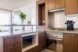 Eine moderne Küche mit Holzschränken, einer Granitarbeitsplatte, einem eingebauten Backofen und einem Edelstahlherd.