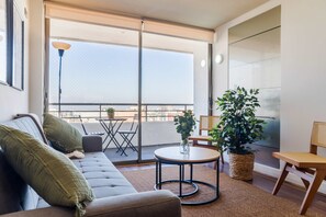A modern living room with a sofa, a small round table, and a potted plant. - Bright 1BR Las Condes  Apartment in Prime location (Las Condes)