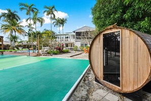 A wooden sauna structure, a swimming pool, and a building with a balcony.