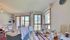 A room with a bed, a dining table with breakfast items, a chair, a television, and a clock on the wall. - Portulans d'Orient - PORT LOUIS (PORT LOUIS)