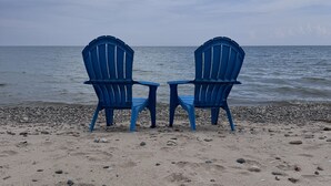 Dos sillas azules mirando al océano en una playa arenosa.