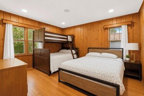 A bedroom with a bunk bed, two single beds, a desk, and a nightstand with a lamp. - Beach front Cottage #3 in Lexington with AC, shared Hot Tub & Pool on Lake Huron (Lexington)