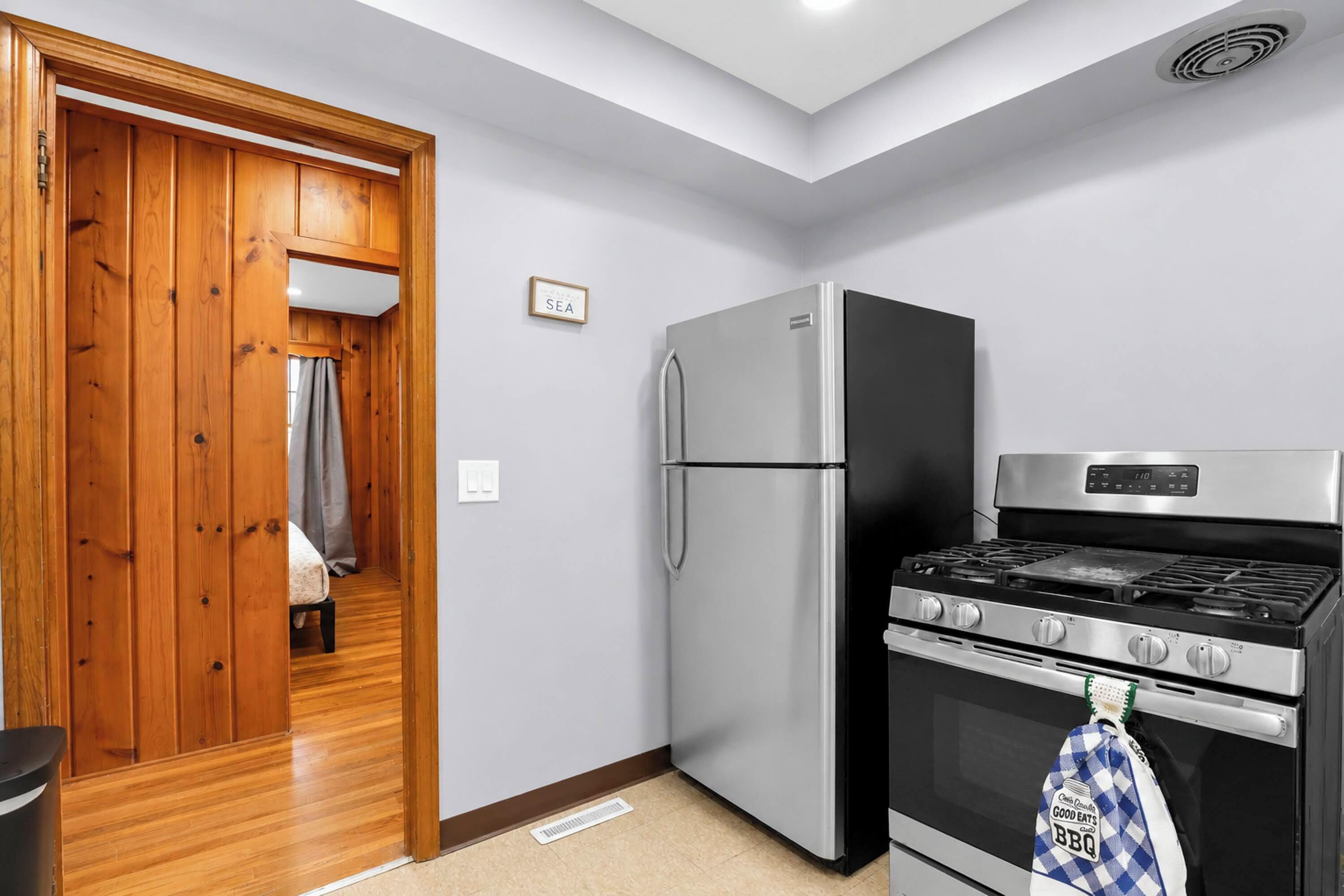 A kitchen with a stainless steel refrigerator, a stove, and a wooden door.