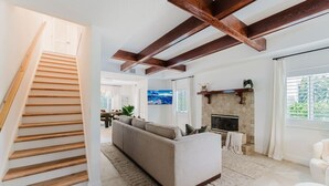 A modern living room with a staircase, a fireplace, and a large window.