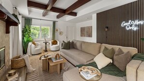 A modern living room with a sofa, armchairs, a coffee table, and a neon sign.