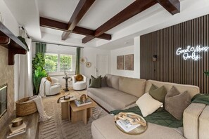Una sala moderna con un sofá, sillones, una mesita de centro y un letrero de neón.