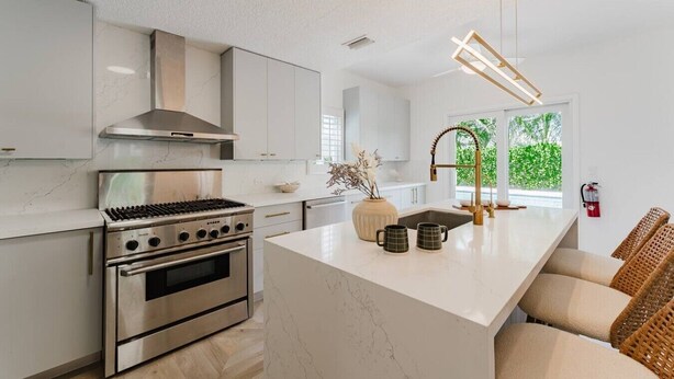 A modern kitchen with stainless steel appliances, a large island, and a view of greenery outside.
