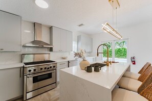 Ett modernt kök med rostfria vitvaror, en stor köksö och utsikt över grönområden utanför.