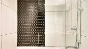 Een moderne badkamer met een douche, betegelde wanden en een glazen scheidingswand met een honingraatmotief.