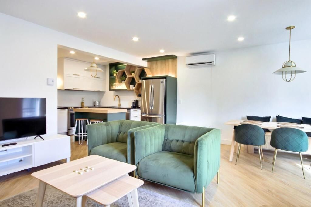A modern living room with a sofa, TV, and dining area.