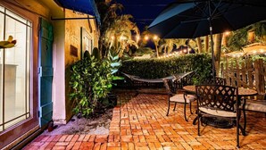 Une terrasse avec un sol en briques, des meubles d’extérieur et un hamac.