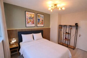Ein Schlafzimmer mit Bett, Nachttisch, Wandregal und einer Tür.