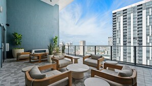 A rooftop lounge with seating and potted plants, overlooking a cityscape. - 501 First Studio Pool  Prime Downtown Miami (Miami)