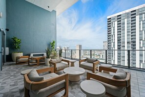 Eine Dachterrasse mit Sitzgelegenheiten und Topfpflanzen mit Blick auf eine Stadtlandschaft.