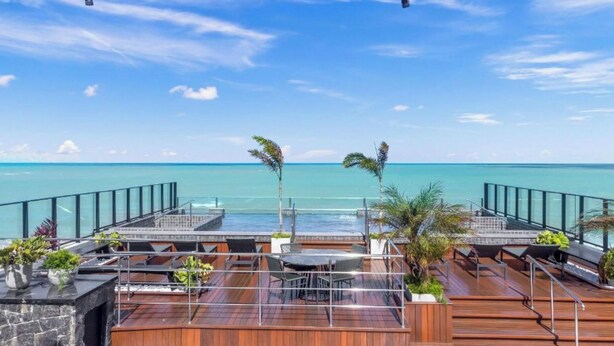 Eine Dachterrasse mit Meerblick, Sitzgelegenheiten im Freien und Kübelpflanzen.