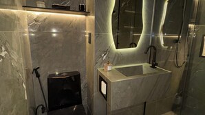 Ein modernes Badezimmer mit Duschkabine aus Glas, integriertem Waschbecken und Marmorfliesenwand.
