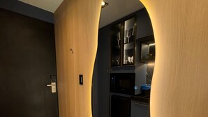 Eine moderne Küche mit dunklen Schränken, einer eingebauten Mikrowelle und einer Wandvertäfelung aus Holz mit Spiegel.