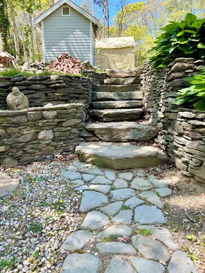 A stone staircase leading to a house, surrounded by a stone wall and greenery. - Charming 2-bedroom apartment in amazing Dennis (Dennis)