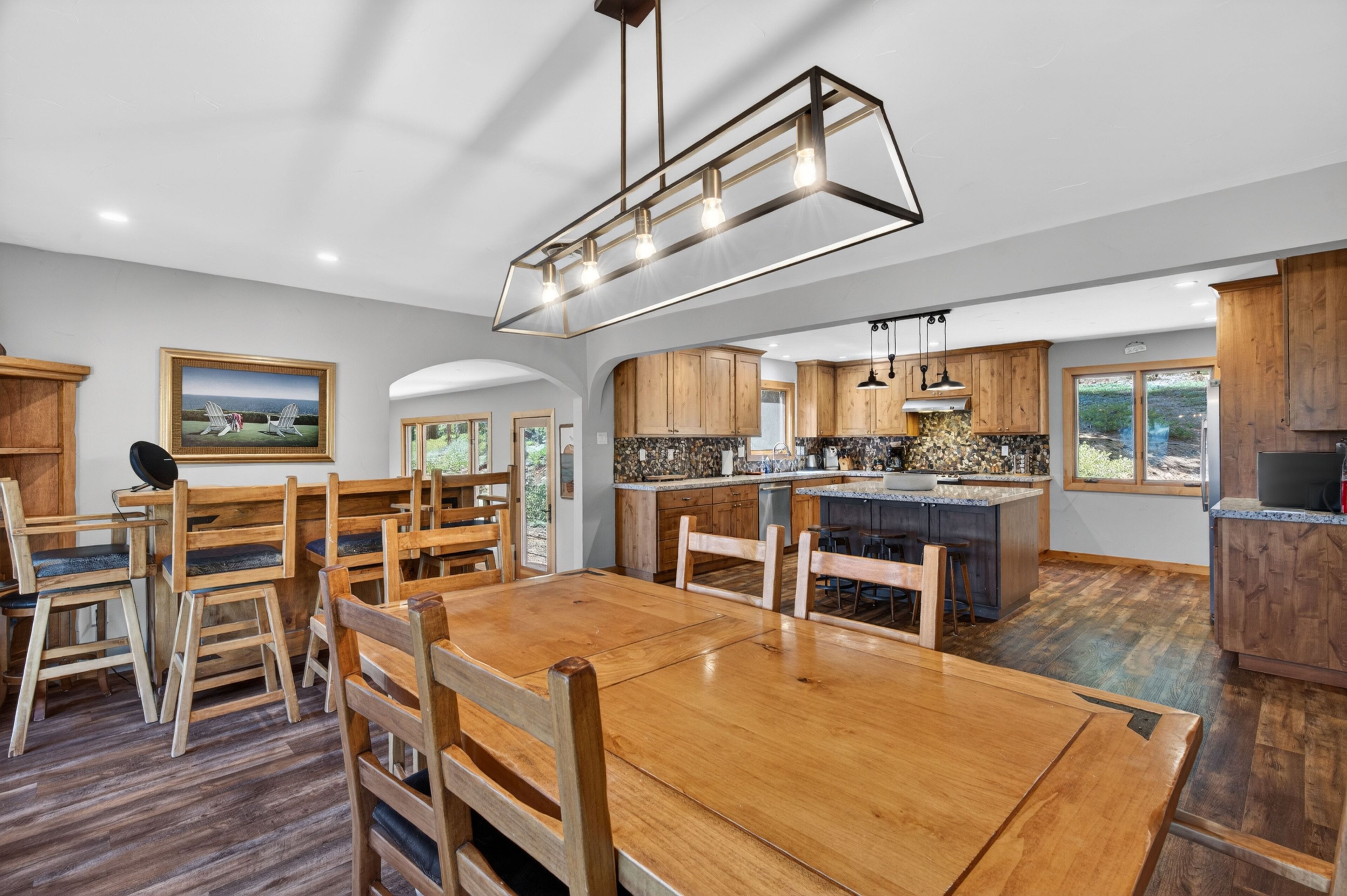 A spacious kitchen with wooden cabinets, a dining area with a wooden table and chairs, and a large island with a sink.
