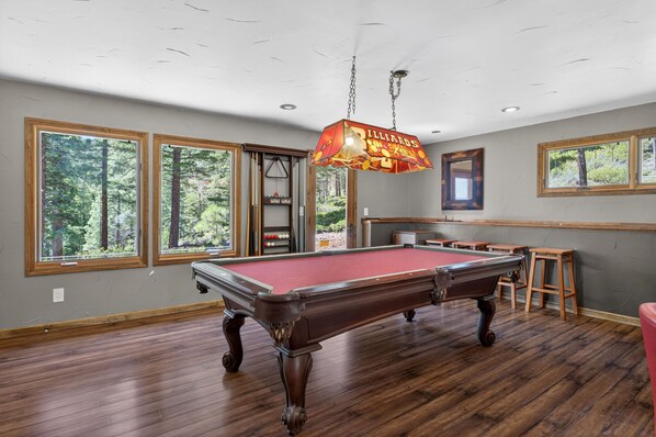 A pool table in a room with large windows, a billiards sign, and a wooden floor. - Tahoe City Mountain Retreat - Near Lake & Skiing (Tahoe City)