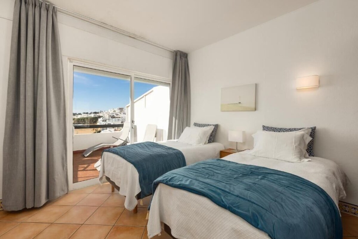 Ein Hotelzimmer mit zwei Betten, einem Balkon und Blick auf die Stadt.