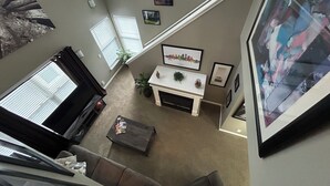 Ein mehrstöckiger Wohnbereich mit Treppe, Sitzgelegenheit und unterschiedlichen Wanddekorationen.