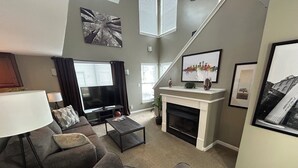 Ein Wohnzimmer mit Sofa, Fernseher, Kamin und Kunstwerken an den Wänden.