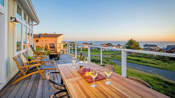 A wooden deck with a table set for dining, outdoor chairs, and a grill. - Cottage by the Sea (Whitethorn)